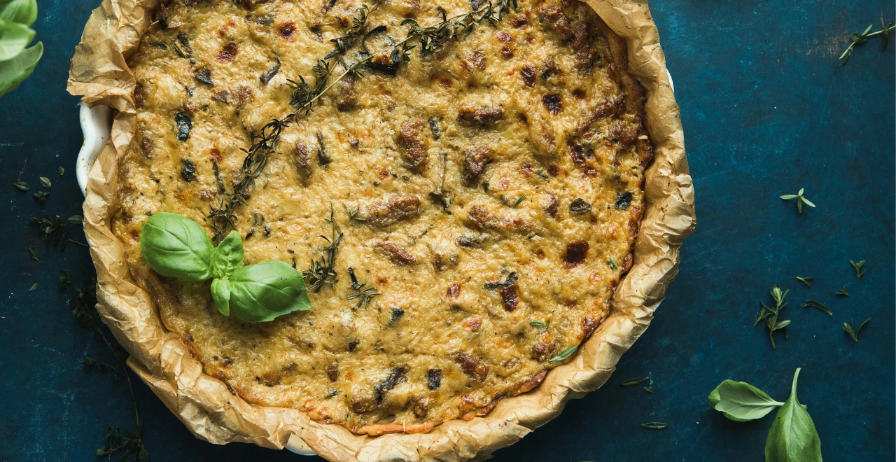 Quiche lorraine entière, parfaitement dorée, sortant du four sur une belle planche en bois rustique, prête à être découpée et servie